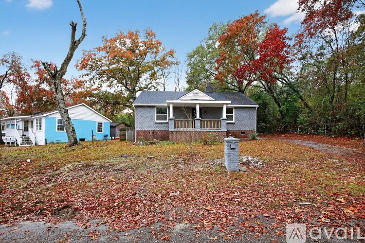 A house with a blue roof is surrounded by trees with red leaves.