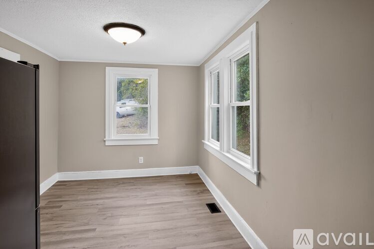 A room with a window and a fridge on the left side.