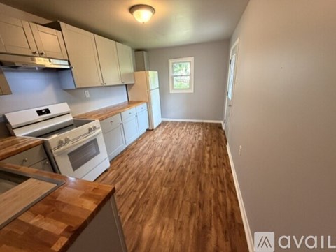 A kitchen with white appliances and wooden floors.