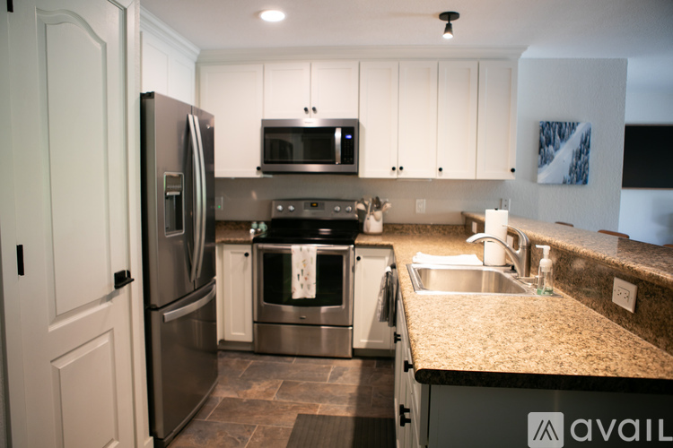 A kitchen with a refrigerator, microwave, oven, sink and cabinets.