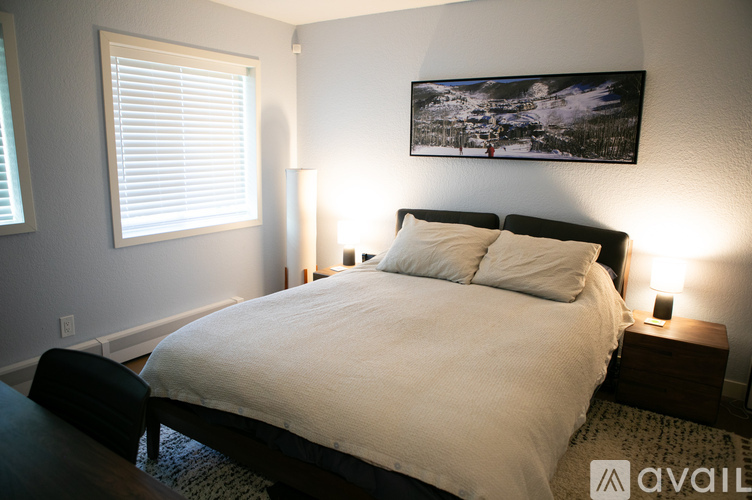 A bedroom with a large bed and a painting on the wall.