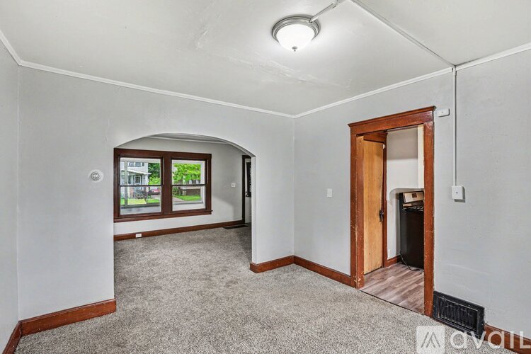 A room with a carpeted floor and a window with a view of trees.
