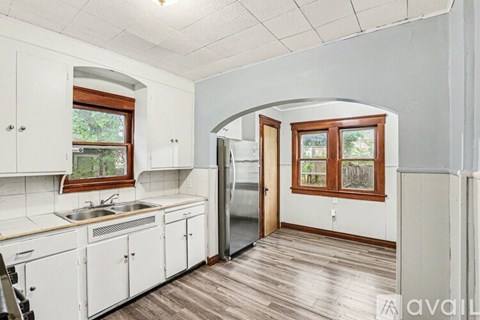 A kitchen with white cabinets and a wooden floor.
