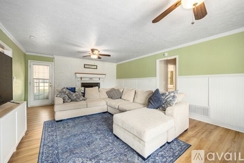 A living room with a white couch and a blue rug.