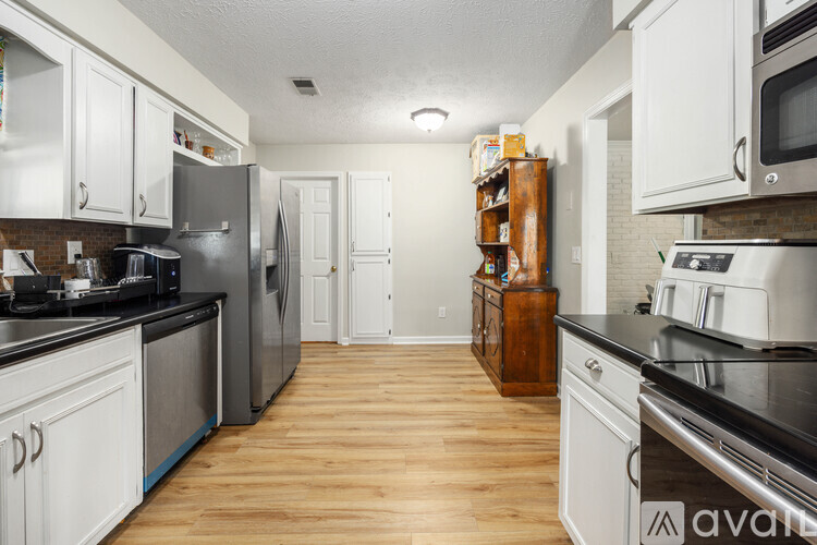 A kitchen with white cabinets and wooden floors.