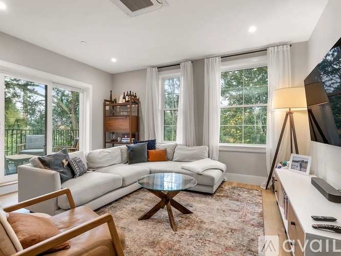 A living room with a white sofa, a glass coffee table, and a wooden chair.