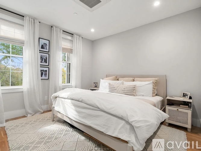 A bedroom with a large bed and a window with curtains.