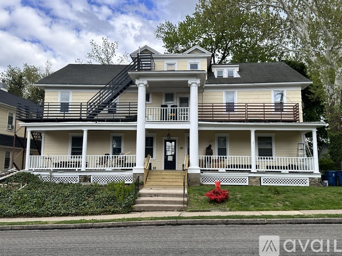 A two-story house with a front porch and a staircase leading to the second floor.