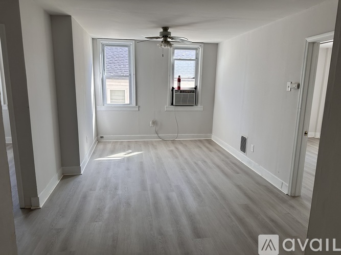 A room with a ceiling fan and two windows.