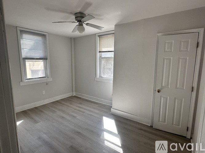 A room with a ceiling fan and two windows.