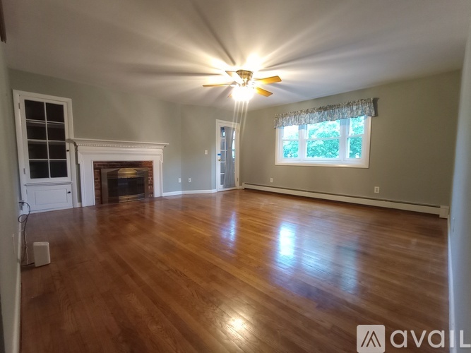 A spacious room with wood flooring and a fireplace.