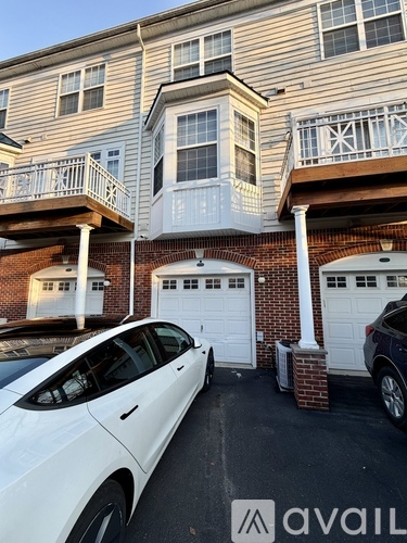 A white car is parked in front of a two-story apartment building.