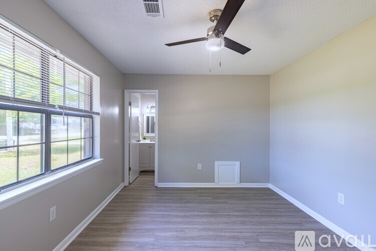 A spacious room with a ceiling fan and a door leading to another room.