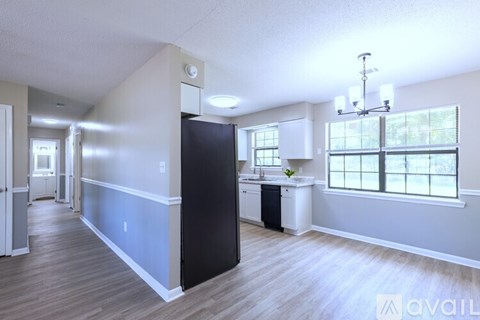 A kitchen with a black refrigerator and white cabinets.