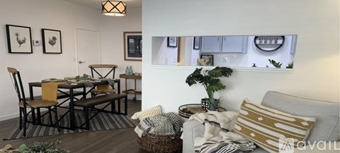 A living room with a grey couch and a dining table with chairs.