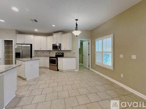 A kitchen with white cabinets and appliances, a tiled floor, and a ceiling light.