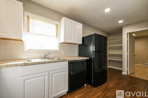 A kitchen with a black fridge and white cabinets.