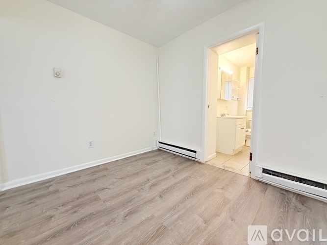A room with a white door and a light switch on the wall.