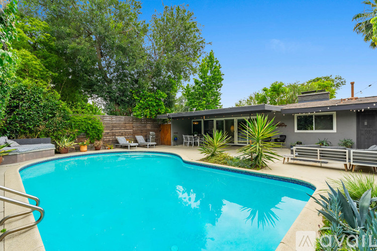 A swimming pool in a backyard with a house in the background.