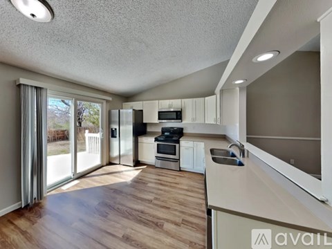 A modern kitchen with white cabinets and a wooden floor.
