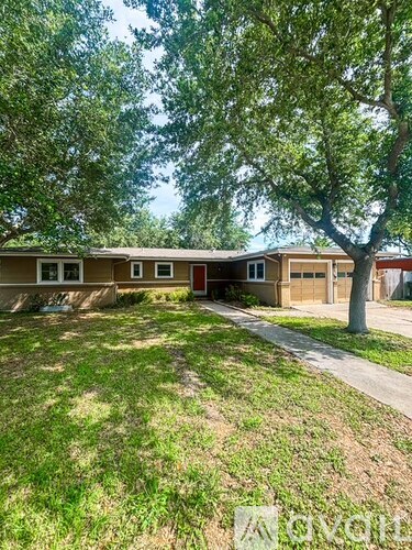 A house with a red door is surrounded by trees.