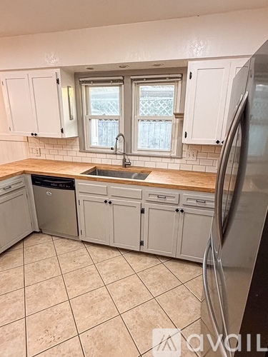 A kitchen with white cabinets and a tiled floor.