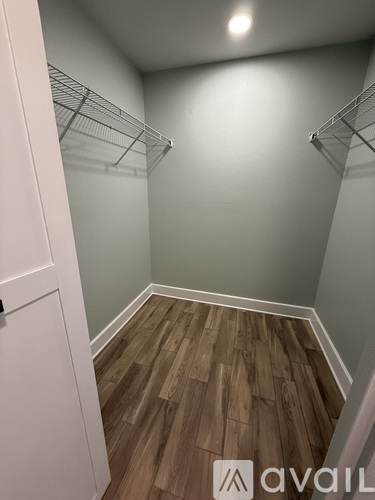 A white closet with wood flooring and a white door.