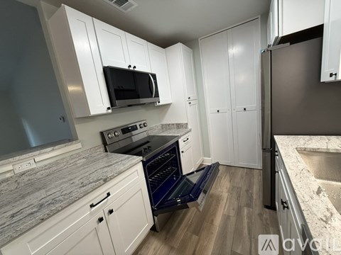 A kitchen with white cabinets and a black microwave.