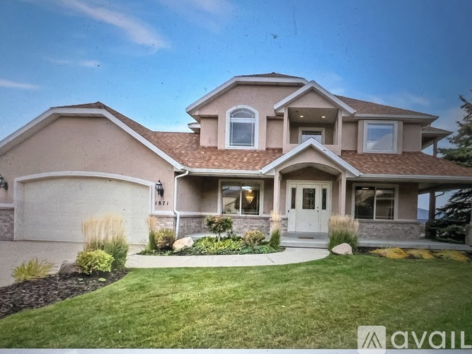 A large house with a driveway and landscaping in front.