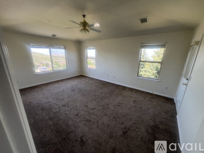 A spacious room with a ceiling fan and carpeted floor.