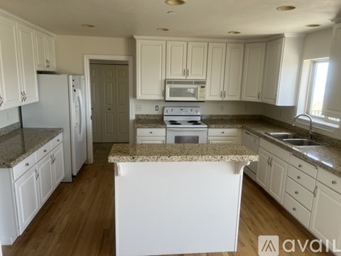 A kitchen with white cabinets and a granite countertop.