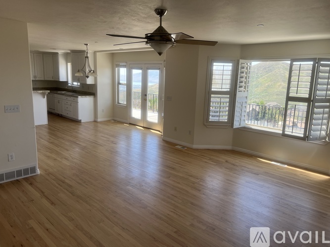 A spacious living room with a ceiling fan and hardwood floors.
