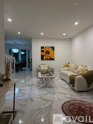 A living room with a white couch, a coffee table, and a sunflower painting on the wall.