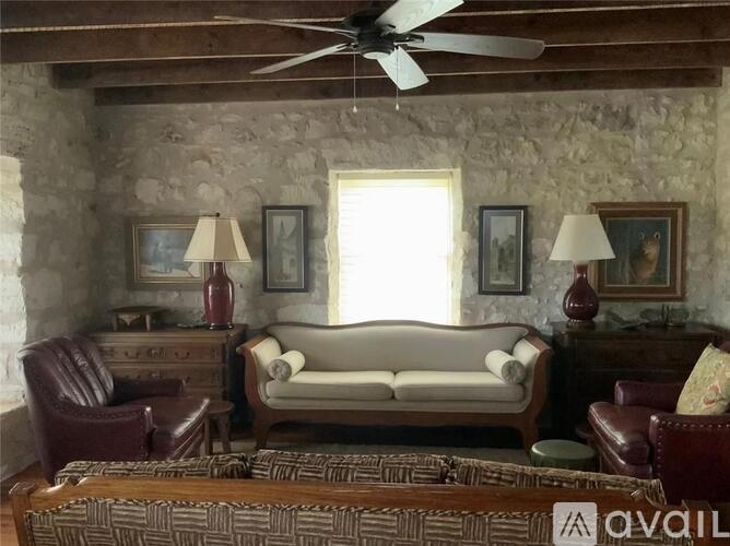 A living room with a couch, chairs, and a rug.