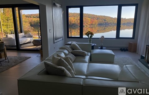 A living room with a large white couch and a view of a lake through the windows.