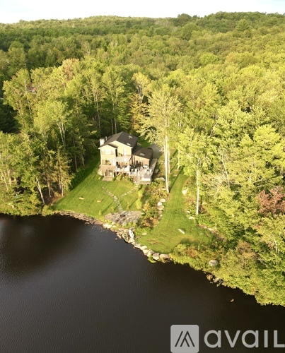 A house is situated on the edge of a lake surrounded by trees.