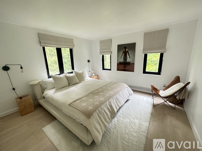 A bedroom with a large bed and a chair.
