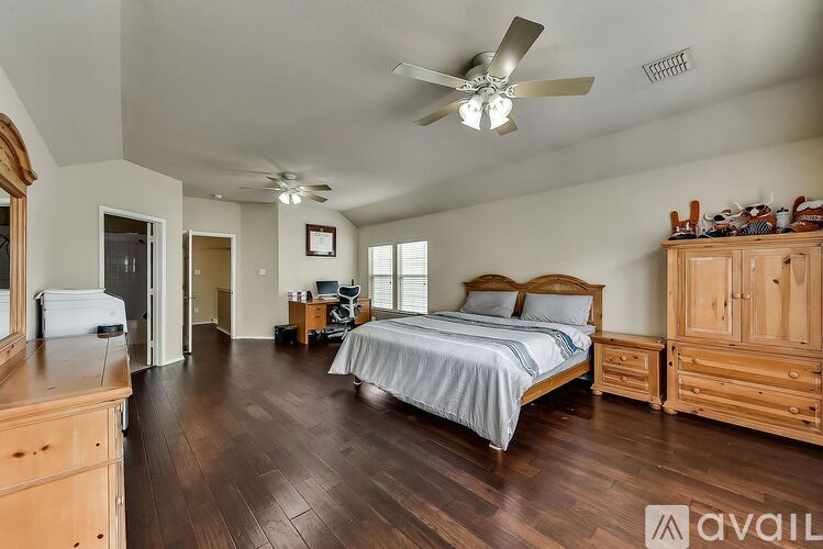 A bedroom with a large bed, wooden furniture, and a ceiling fan.