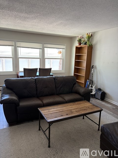 A living room with a brown leather couch and a wooden coffee table.