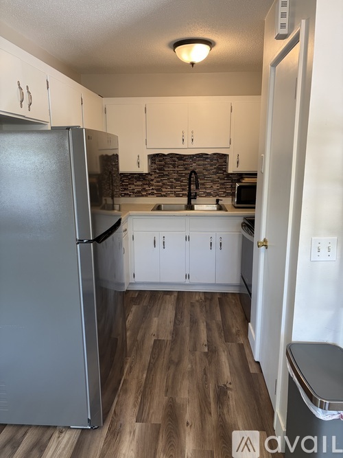 A kitchen with a refrigerator, cabinets, and a microwave.