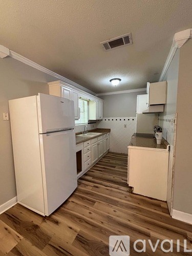 A kitchen with white appliances and wooden floors.