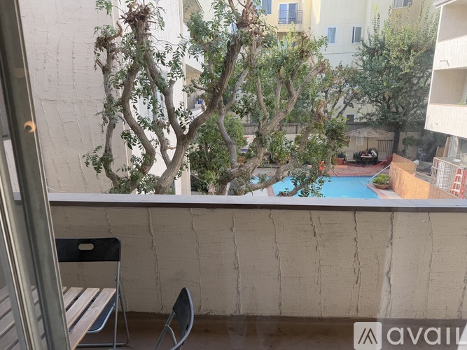 A balcony with a chair and a table overlooking a pool.