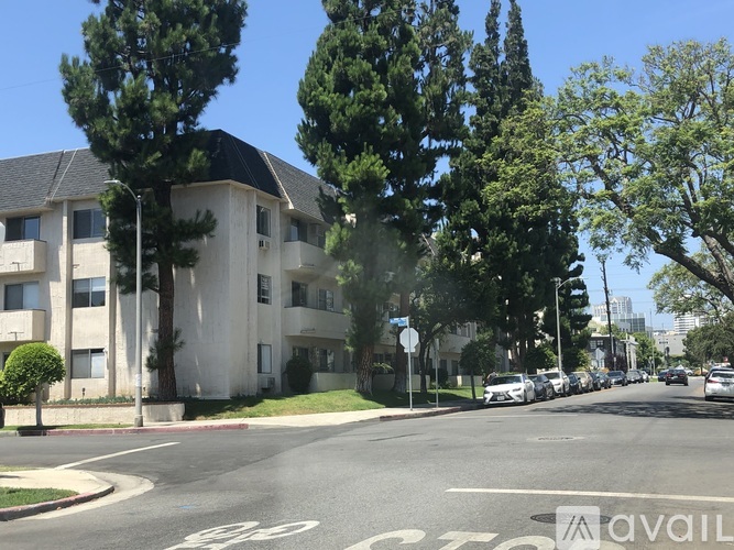A street view of a residential area with apartment buildings and parked cars.