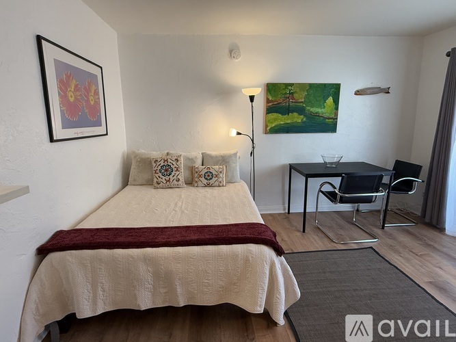 A bedroom with a bed, a chair, and a painting on the wall.