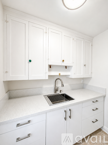 A kitchen with white cabinets and a sink.