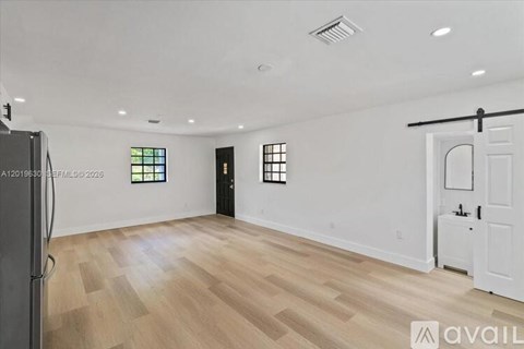 A spacious room with wooden flooring and white walls.
