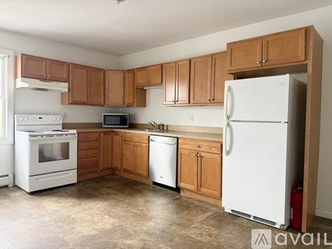 A kitchen with white appliances and wooden cabinets.