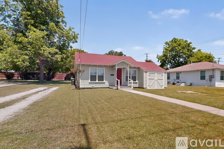 A house with a red roof is surrounded by a grassy lawn.
