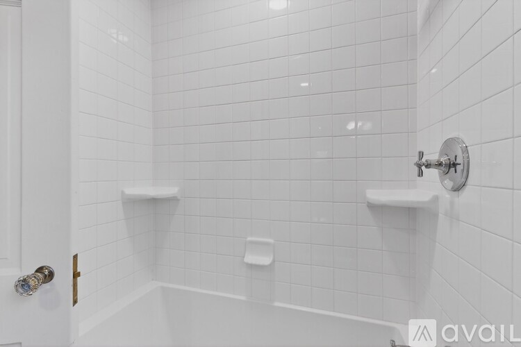 A white tiled bathroom with a shower and a toilet.