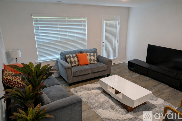 A living room with a grey couch, a white coffee table, and a black television.
